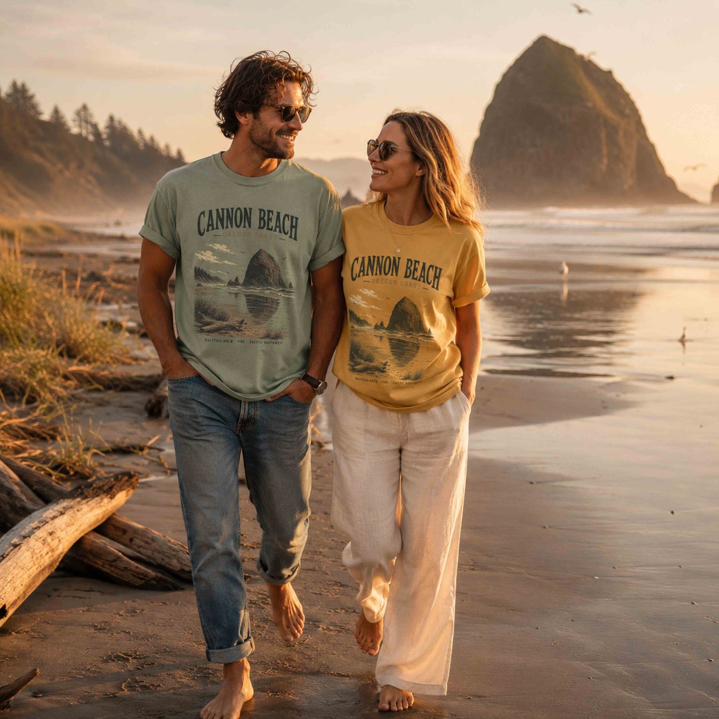 Couple wearing Cannon Beach Oregon Coast graphic t-shirts in Bay and Mustard near Haystack Rock