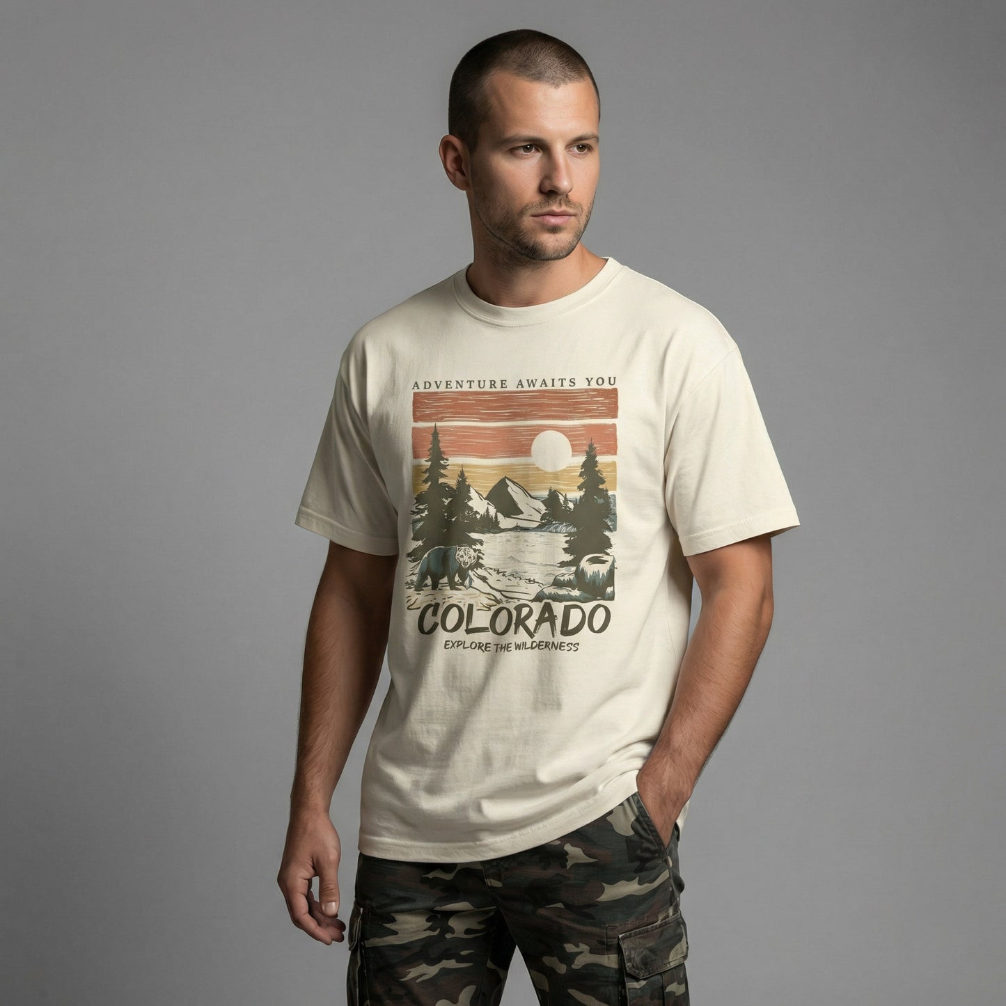 Man wearing a relaxed-fit cream t-shirt with a vintage Colorado wilderness graphic, paired with camouflage pants.