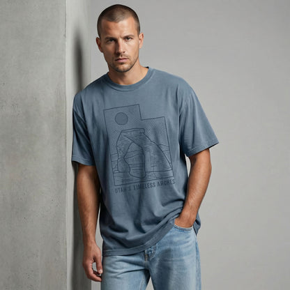 Man standing and looking forward, modeling a relaxed-fit blue Utah arches graphic tee and light blue jeans.