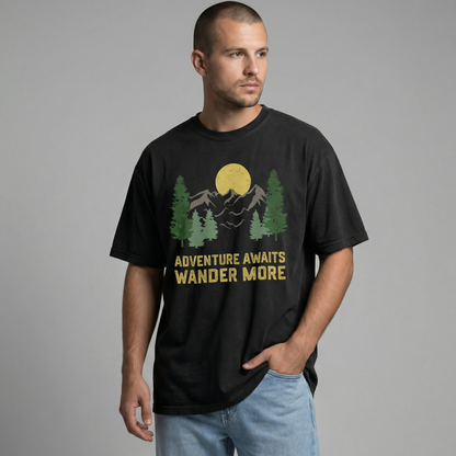 Man looking off-camera wearing a relaxed-fit black t-shirt with a vintage mountain and forest graphic reading "Adventure Awaits Wander More".