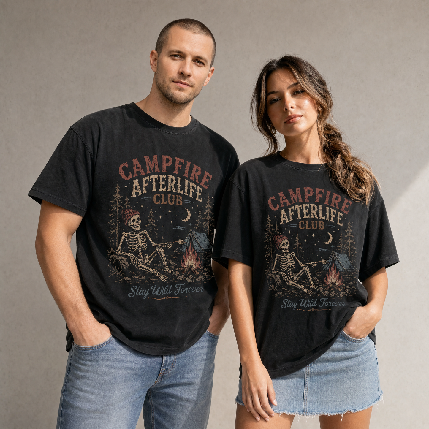Vintage skeleton camping graphic tee featuring a skeleton roasting a marshmallow by a campfire with tent, pine trees, moon, and retro distressed artwork on a black shirt.