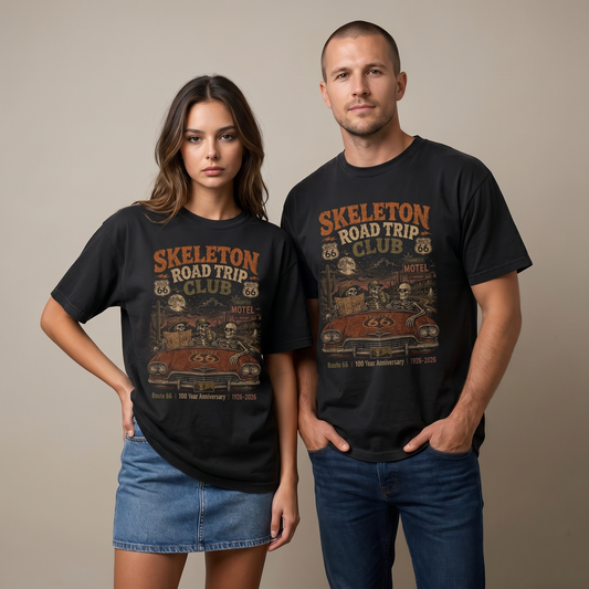 Unisex black Route 66 graphic tee featuring Skeleton Road Trip Club artwork with skeletons in a vintage car, haunted motel, desert cactus, moon, and 1926–2026 anniversary text.