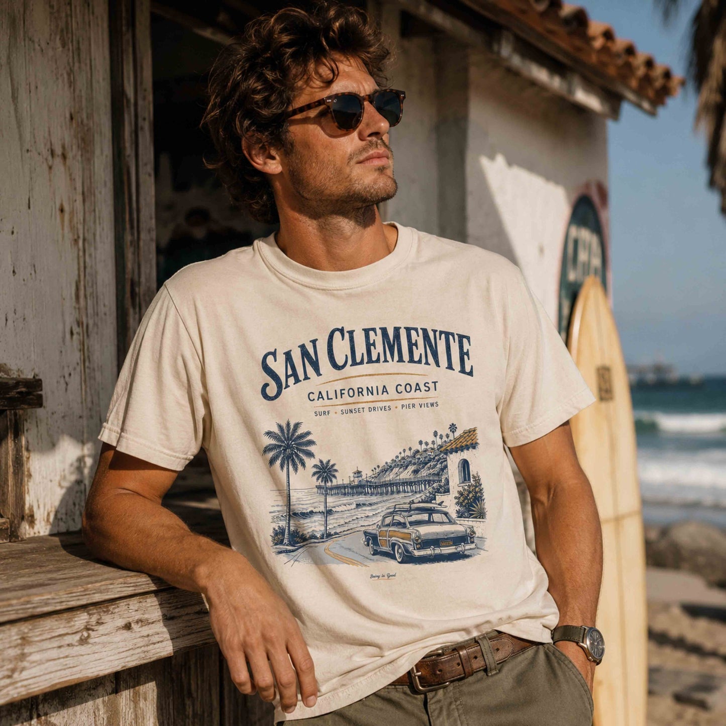 Man wearing Ivory San Clemente California Coast graphic t-shirt near a surf shack